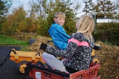 Two young children on a toy digger and in a bread tray